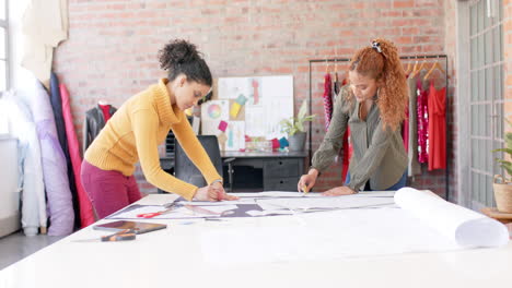 Happy-diverse-female-fashion-designers-discussing-fabrics-in-studio,-slow-motion