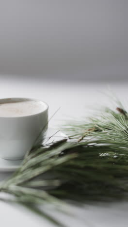 Vertical-video-of-mug-of-christmas-chocolate-with-fir-tree-branch-and-copy-space-on-white-background