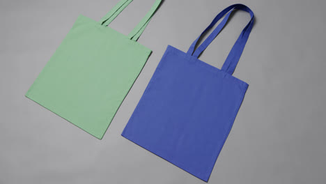 Nahaufnahme-Von-Grünen-Und-Blauen-Taschen-Auf-Grauem-Hintergrund,-Mit-Kopierraum,-Zeitlupe