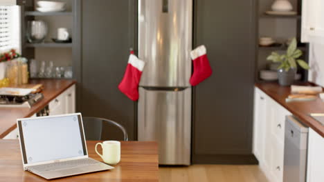 Laptop-with-blank-screen-on-kitchen-countertop-at-christmas,-slow-motion,-copy-space