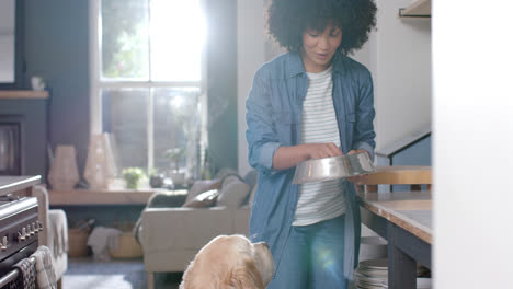 Happy-biracial-woman-serving-dog-food-at-home,-slow-motion