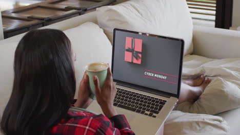 Biracial-woman-on-couch-with-coffee-using-laptop-for-online-shopping,-slow-motion