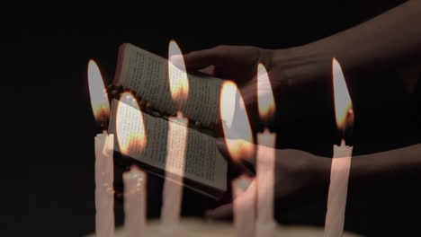 Composite-video-of-burning-candles-against-woman-hands-holding-bible-and-rosary-praying