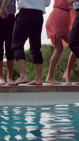 Vertical-video-of-friends-standing-by-a-poolside,-ready-to-jump-in,-with-copy-space