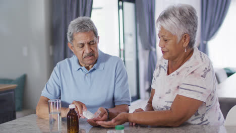 Senior-biracial-couple-talking-and-taking-pills