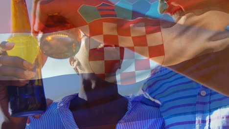 Composite-Video-Einer-Wehenden-Kroatischen-Flagge-über-Einer-Gruppe-Unterschiedlicher-Freunde,-Die-Im-Freien-Mit-Bier-Anstoßen