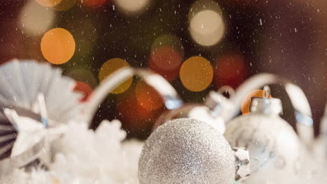 Animation-of-snowfall-over-baubles-against-lens-flares-in-background