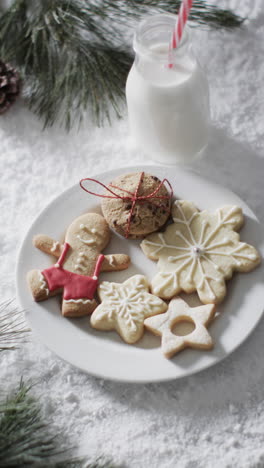 Vertical-video-of-bottle-of-milk,-cookies-with-copy-space-on-snow-background