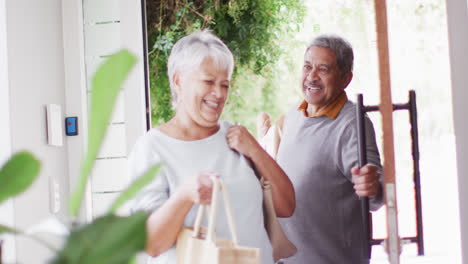 Happy-senior-diverse-couple-coming-home-with-groceries
