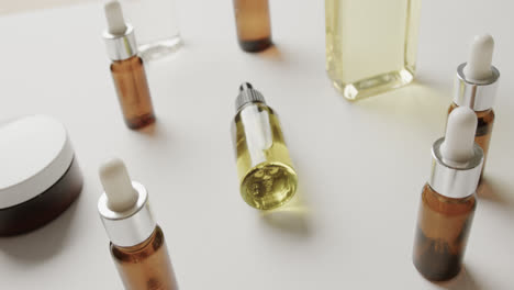 Close-up-of-cream-tub-and-glass-bottles-with-copy-space-on-white-background