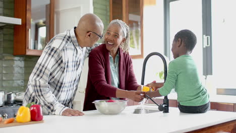 Glückliche-Afroamerikanische-Großeltern-Und-Enkelkinder-Beim-Gemüsewaschen-In-Der-Küche,-Zeitlupe