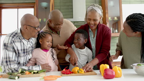 Glückliche-Afroamerikanische-Mehrgenerationenfamilie,-Die-In-Der-Küche-Gemüse-Schneidet,-Zeitlupe