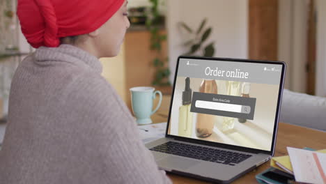 Biracial-woman-at-table-using-laptop,-shopping-online-for-beauty-products,-slow-motion
