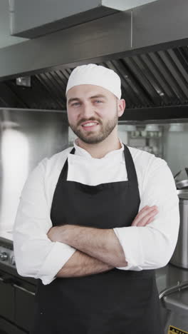 Feliz-Chef-Caucásico-De-Pie-Con-Los-Brazos-Cruzados-En-La-Cocina,-Cámara-Lenta,-Vertical