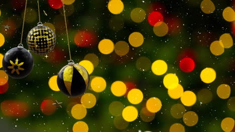 Swinging-black-and-gold-christmas-baubles-over-falling-snow-and-yellow-and-red-bokeh-light-spots