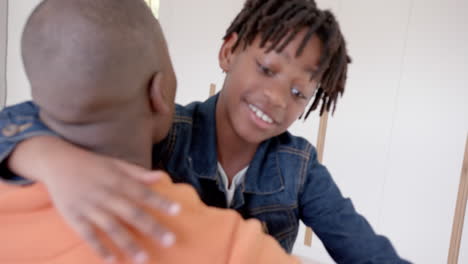 Happy-african-american-father-and-son-embracing-at-home,-slow-motion