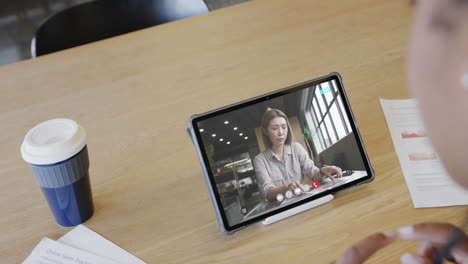 Caucasian-businesswoman-on-tablet-video-call-with-caucasian-female-colleague-on-screen