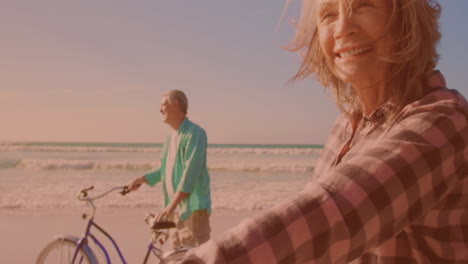 Glückliches-Kaukasisches-älteres-Paar,-Das-Zusammen-Am-Strand-Fahrrad-Fährt