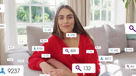 Animation-of-social-media-icons-and-numbers-over-caucasian-woman-at-home