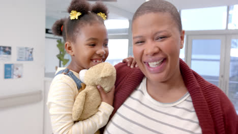 Retrato-De-Una-Feliz-Madre-Afroamericana-Sosteniendo-A-Su-Hija-Con-Mascota-En-El-Hospital,-Cámara-Lenta
