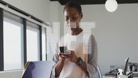 Animation-of-nft-text-banner-against-african-american-woman-using-smartphone-at-office
