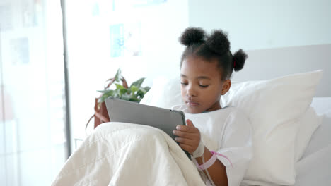 African-american-girl-using-tablet-in-hospital-bed,-slow-motion