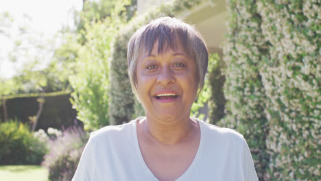 Portrait-of-happy-senior-biracial-woman-smiling-and-laughing-in-garden,-in-slow-motion