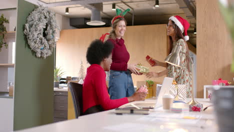 Happy-diverse-female-creative-colleagues-giving-christmas-presents-in-office,-slow-motion