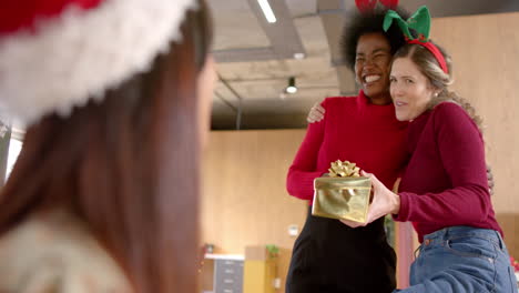 Happy-diverse-female-creative-colleagues-giving-christmas-presents-in-office,-slow-motion