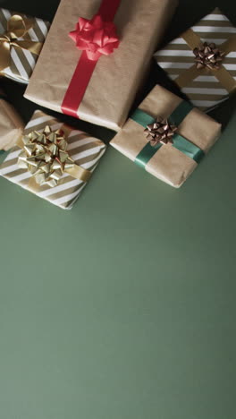Vertical-video-of-christmas-presents-and-copy-space-on-green-background