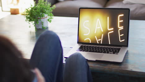 Knees-of-woman-at-table-using-laptop,-online-shopping-during-sale,-slow-motion