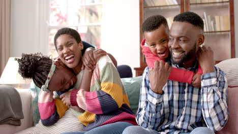 Retrato-De-Felices-Padres-Afroamericanos,-Hijo-E-Hija-Sentados-En-Un-Sofá-En-Casa,-Cámara-Lenta