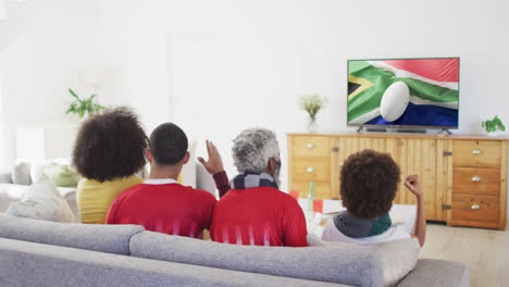 Gemischtrassige-Familie-Vor-Dem-Fernseher-Mit-Rugbyball-Auf-Der-Flagge-Südafrikas-Auf-Dem-Bildschirm