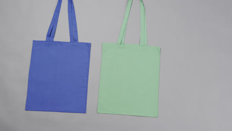 Nahaufnahme-Von-Blauen-Und-Grünen-Taschen-Auf-Grauem-Hintergrund,-Mit-Kopierraum,-Zeitlupe