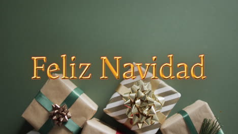 Feliz-navidad-text-in-orange-over-christmas-gifts-on-green-background