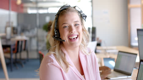 Portrait-of-happy-caucasian-casual-businesswoman-using-phone-headset-in-office,-slow-motion