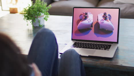 Knees-of-woman-at-table-using-laptop,-online-shopping-for-gamepads,-slow-motion