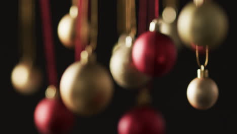 Video-of-gold-and-red-christmas-baubles-decorations-with-copy-space-on-black-background