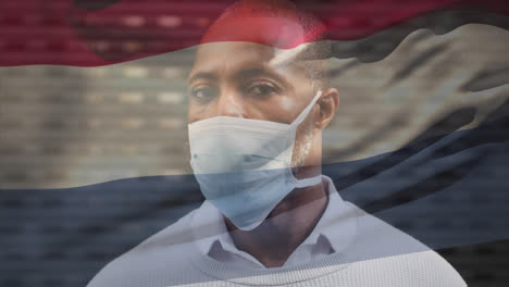 Animation-Der-Niederländischen-Flagge-über-Dem-Porträt-Eines-Afroamerikanischen-Mannes-Mit-Gesichtsmaske-Auf-Der-Straße