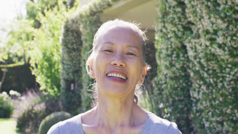 Portrait-of-happy-senior-asian-woman-smiling-in-garden,-in-slow-motion