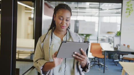 Happy-african-american-casual-businesswoman-using-tablet-standing-in-office,-slow-motion