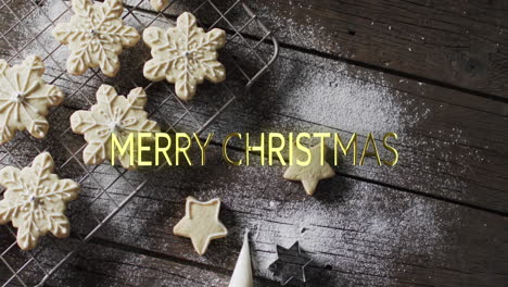 Merry-christmas-text-in-yellow-over-snowflake-cookies-on-wooden-background