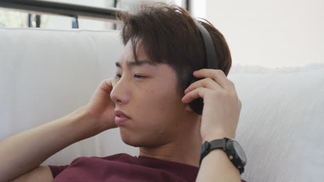 Asiatischer-Männlicher-Teenager-Hört-Musik-Mit-Kopfhörern-Im-Wohnzimmer