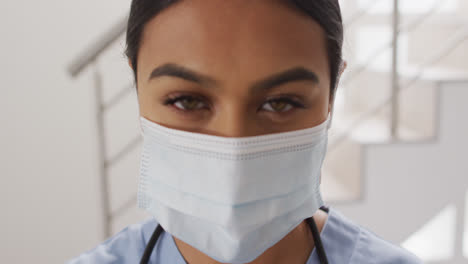 Video-Einer-Gemischtrassigen-Ärztin,-Die-Eine-Gesichtsmaske-Aufsetzt-Und-In-Die-Kamera-Blickt