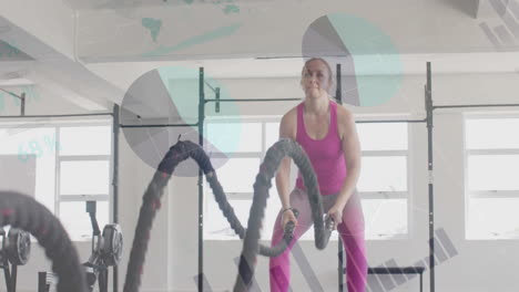 Animation-of-data-on-interface-over-caucasian-woman-cross-training-with-battle-ropes-at-gym