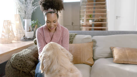 Happy-biracial-woman-petting-golden-retriever-dog-at-home,-slow-motion,-copy-space