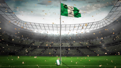 Animación-De-Confeti-Dorado-Cayendo-Ondeando-La-Bandera-De-Nigeria-Contra-El-Estadio-Deportivo