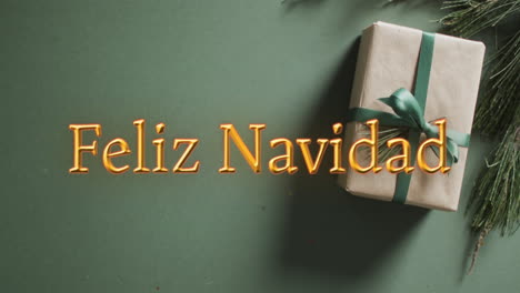 Feliz-navidad-text-in-orange-over-christmas-gift-on-green-background