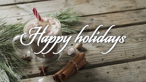 Happy-holidays-text-in-white-over-christmas-hot-chocolate-and-cinnamon-sticks-on-wooden-background