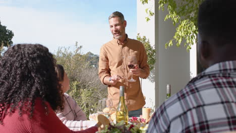 Happy-caucasian-man-toasting-on-thanksgiving-celebration-meal-in-sunny-garden